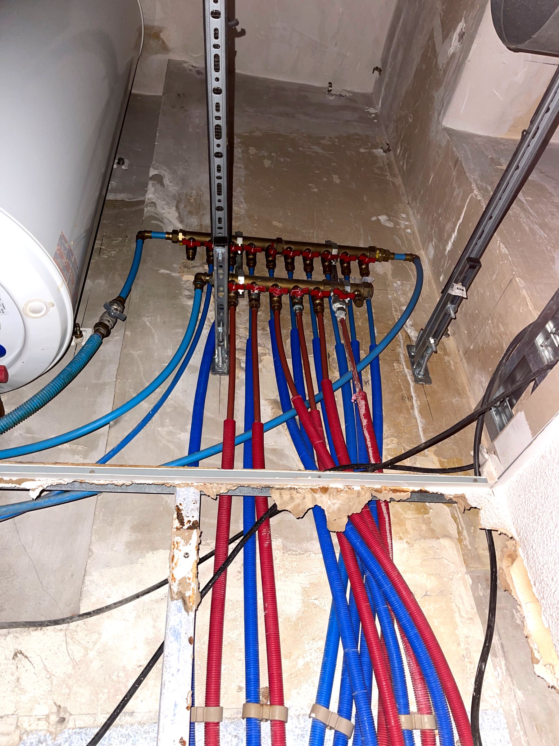 Nourrices de distribution en laiton avec vannes d'isolement, départs PER eau chaude (rouge) et eau froide (bleu) sous gaine